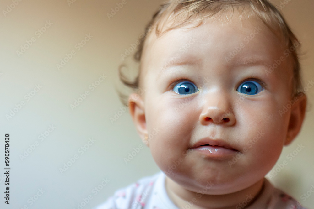 Blond baby girl face indicating surprise, wide open blue eyes with plump cheeks Blond baby girl face indicating surprise, wide open blue eyes with plump cheeks