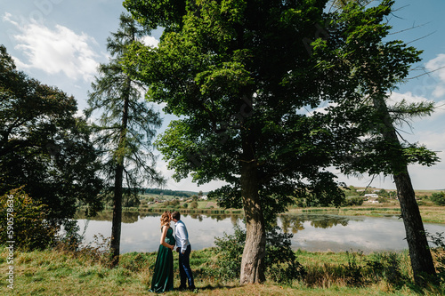 Photo of pregnant happy woman and cheerful man in park. Romantic moments pregnant. Couple walking in nature.