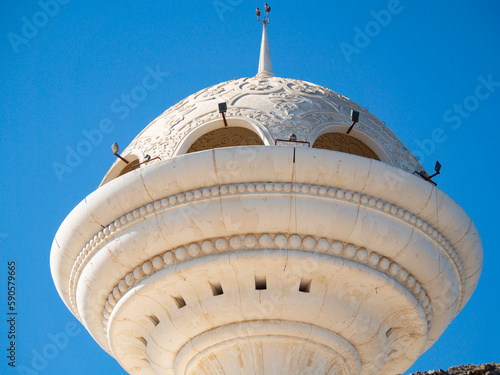 Close up view to the Riyam Park monument dome through the palm leaves. Muscat, Oman.