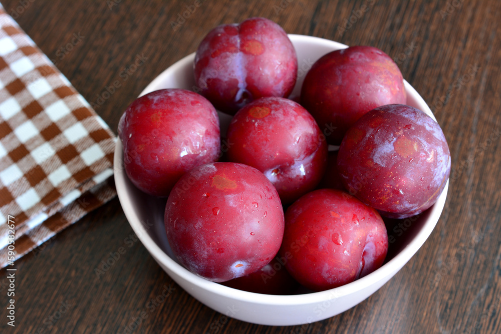 A bowl of plums on a table isolated, close-up A bowl of plums on a table isolated, close-up