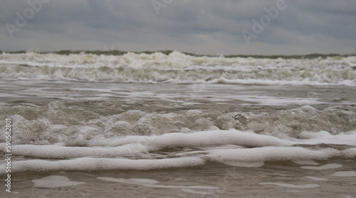 Die Wellen der Nordsee  in Nahaufnahme mit dunklen Wolken eines aufziehenden Sturms
