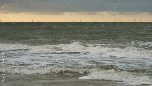Die bedrohliche Nordsee mit dunklen Wolken eines aufziehenden Sturms und Windrädern am Horizont