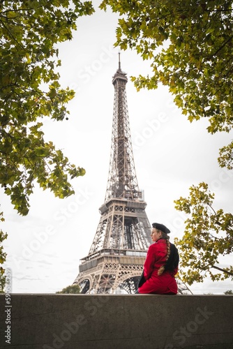 Fototapeta Naklejka Na Ścianę i Meble -  Girl wearing a red coat in front of Eiffel Tower