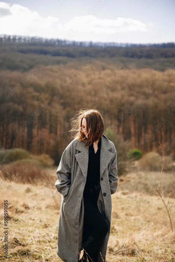 young girl in a long coat in the mountains. A girl walks on top of a mountain. young girl in a long coat in the mountains. A girl walks on top of a mountain.