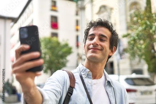 young caucasian man taking a selfie while traveling in a new city.