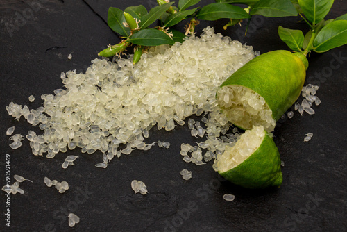 Delicious white citrus caviar on the black slate slab decorated with a green plants sprig and сut finger-shaped ripe fruit, close-up.  Microcitrus australasica, Australian finger lime, Faustrimedin