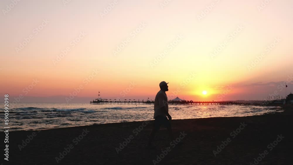 Epic cinematic shot of tourist man walking at sea beach during amazing sunset, walking forward and parallel to camera. Epic cinematic shot of tourist man walking at sea beach during amazing sunset, walking forward and parallel to camera.