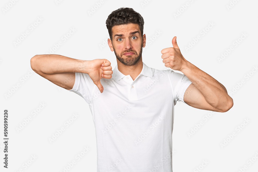Fototapeta premium Young handsome man isolated showing thumbs up and thumbs down, difficult choose concept