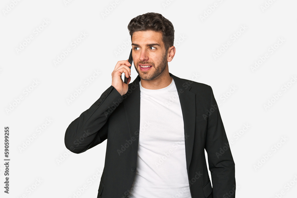 Young businessman multitasking with ease, speaking confidently on his mobile phone in a professional setting.