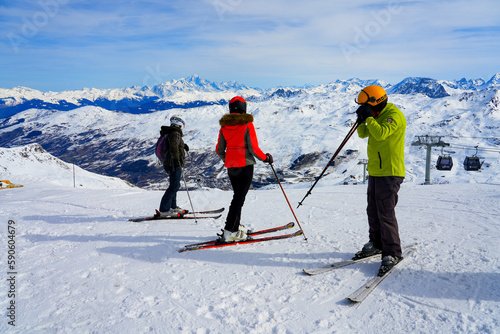 Les Ménuires, France - March 16, 2023 : Skiers getting ready to go down the slopes of La Masse mountain above Les Ménuires ski resort while contemplating the view over the Mont Blanc in the distance