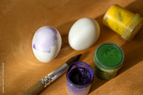 chicken eggs and paints with a brush on a wooden surface. Easter. children's entertainment