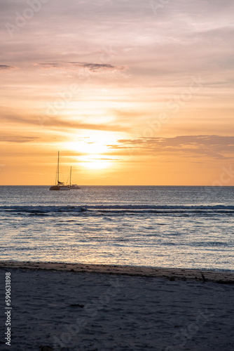 sunset over ocean with sailboat