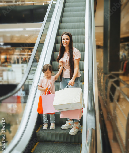 mother and little girl on the escalator in the mall.Mother and daughter in the mall. A young mother and her little child are shopping together. photo