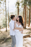 Young happy couple in love hugging smiling and having fun in the mountains. High quality photo. A girl in a beautiful white dress
