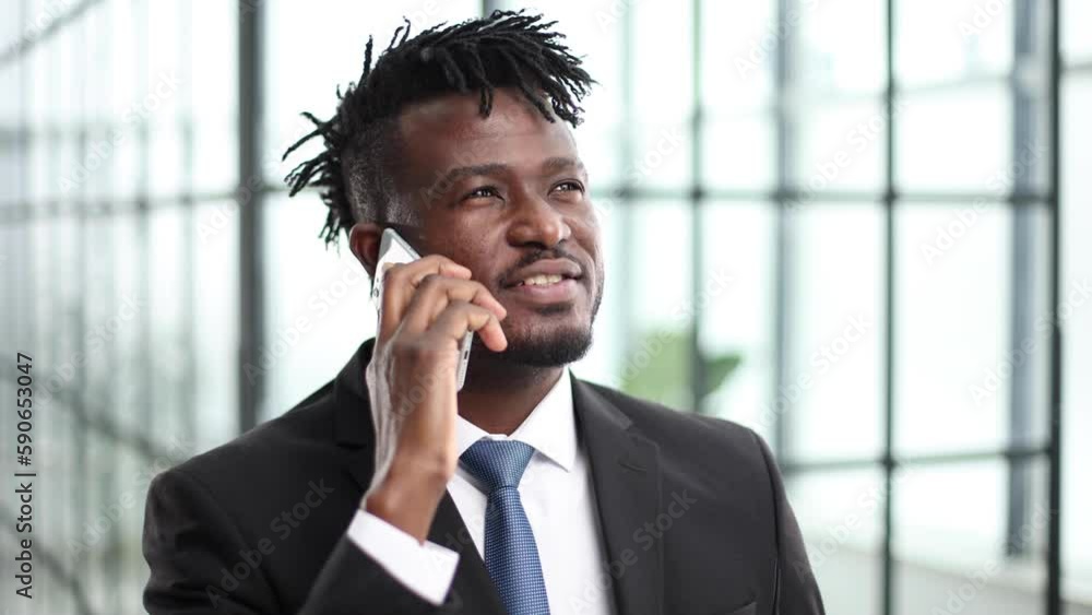 Cheerful and smiling businessman in a suit talking on the phone in the office Cheerful and smiling businessman in a suit talking on the phone in the office