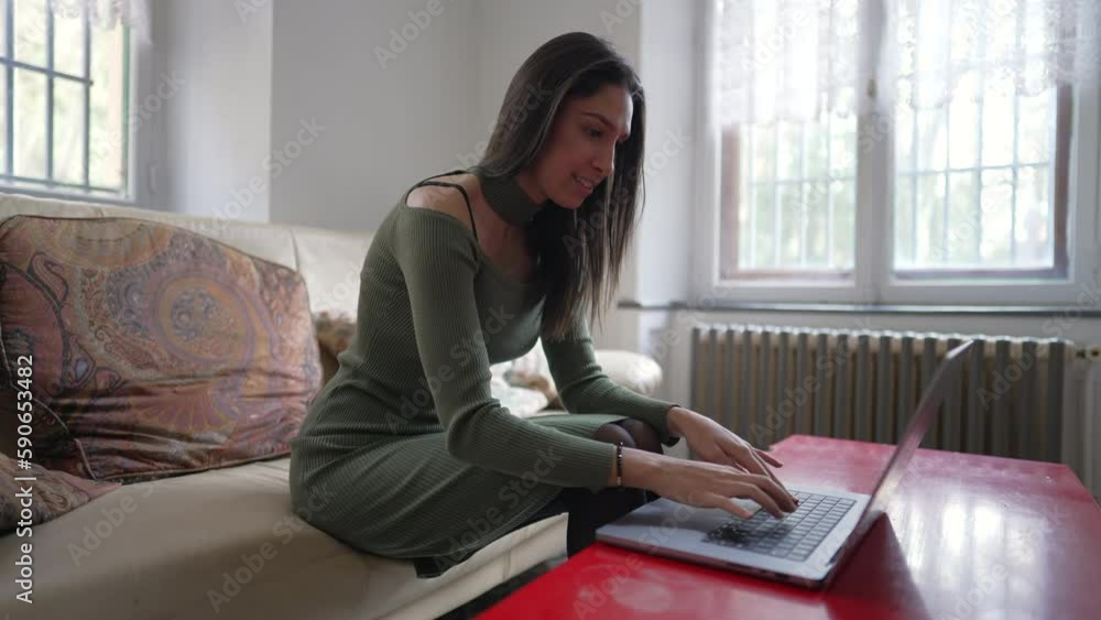 One young woman typing on computer laptop at home. One Middle Eastern female person in 20s using modern technology device indoors One young woman typing on computer laptop at home. One Middle Eastern female person in 20s using modern technology device indoors