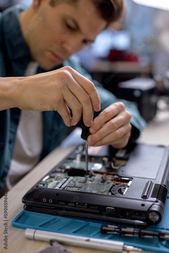 technician hold the screwdriver for repairing the laptop. computer hardware, repairing, upgrade and technology. professional technicial at workplace concentrated. focus on hands technician hold the screwdriver for repairing the laptop. computer hardware, repairing, upgrade and technology. professional technicial at workplace concentrated. focus on hands