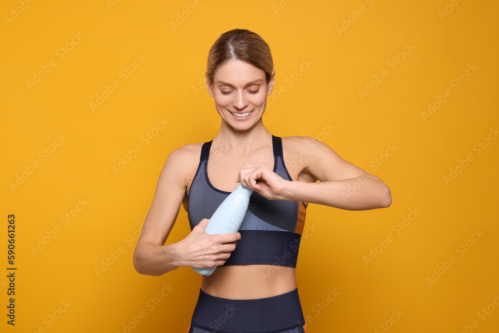Sportswoman with thermo bottle on yellow background Sportswoman with thermo bottle on yellow background
