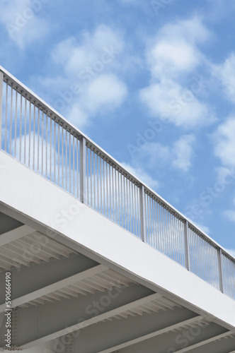 Steel bridge girder span, blue grey metal guardrails, modern industrial flyover overpass perspective large vertical closeup, blank empty copy space, sunny summer sky cloudscape white clouds background