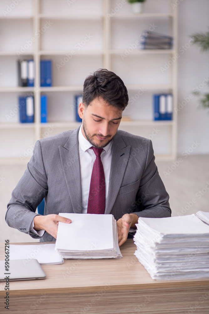 Young male employee and too much work in the office Young male employee and too much work in the office