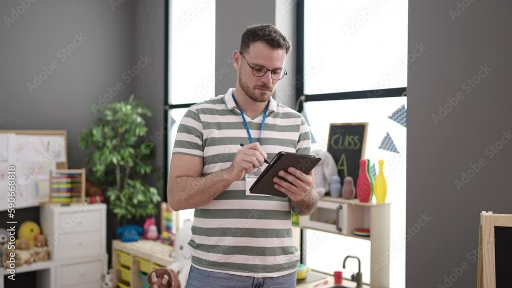 Young caucasian man working as teacher with tablet at kindergarten Young caucasian man working as teacher with tablet at kindergarten