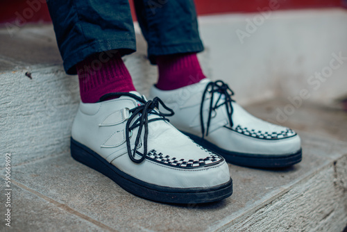 Close up of these white creepers sneakers made of genuine leather with black soles that men wear to sit on. These casual yet elegant shoes are handmade by home shoe craftsmen