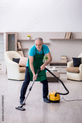 Old male contractor cleaning the house