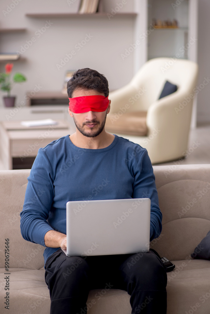 Blindfolded young male freelancer working from home Blindfolded young male freelancer working from home