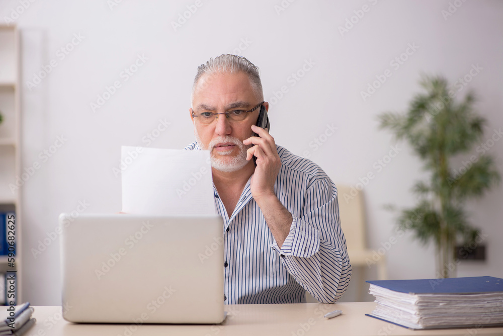 Old male employee working at workplace Old male employee working at workplace