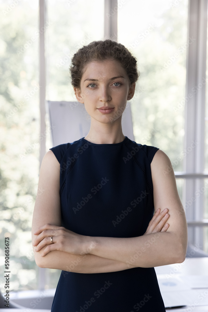 Serious confident attractive young businesswoman vertical front portrait. Professional, employee, intern, business teacher woman standing in boardroom, looking at camera Serious confident attractive young businesswoman vertical front portrait. Professional, employee, intern, business teacher woman standing in boardroom, looking at camera