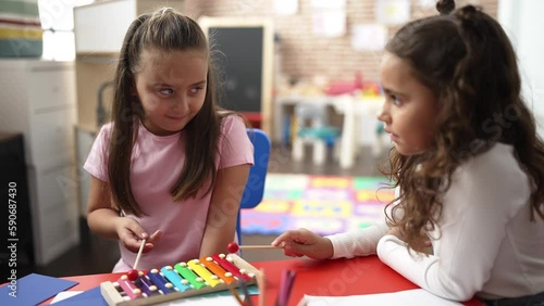 Adorable girls playing xylophone standing at kindergarten photo