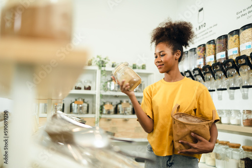 Young African American woman is choosing and shopping for organic products in refill store with reusable bag. No plastic Conscious Minimalism Vegan  sustainable plastic free Lifestyle Concept.