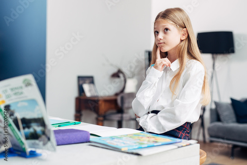 Girl sits thoughtfully at home while doing her lessons, remembering or memorizing information photo
