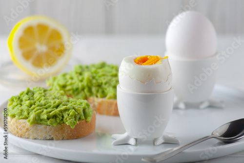 Soft-boiled egg and open bread sandwich with avocado on the table. Traditional food for a healthy breakfast.