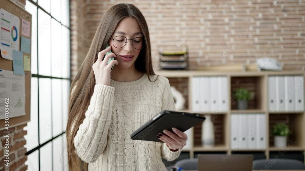 Young beautiful hispanic woman business worker talking on smartphone using touchpad at office