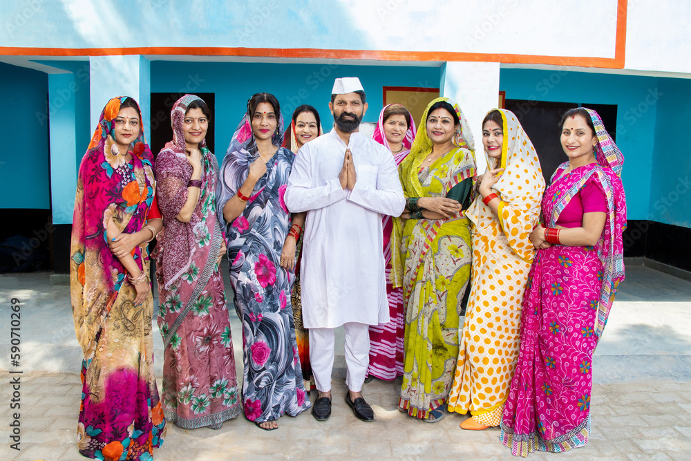 Indian man politician standing doing namaste with group of traditional women. Concept of election and vote. - obrazy, fototapety, plakaty 