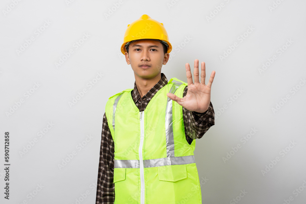 Young asian construction worker doing stop gesture with palm hand isolated on white background. Stop sign concept. Young asian construction worker doing stop gesture with palm hand isolated on white background. Stop sign concept.