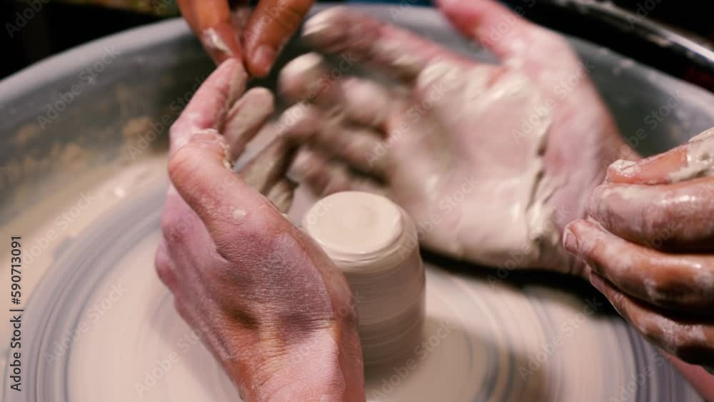 A skilled female potter works on a potter's wheel in close-up. An open class is in progress. The concept of handicraft, art and craft. Slow motion A skilled female potter works on a potter's wheel in close-up. An open class is in progress. The concept of handicraft, art and craft. Slow motion