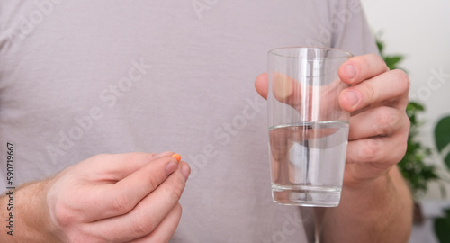 Caucasian man taking a pill and drinking a glass of water. Health, medicine, treatment concept.