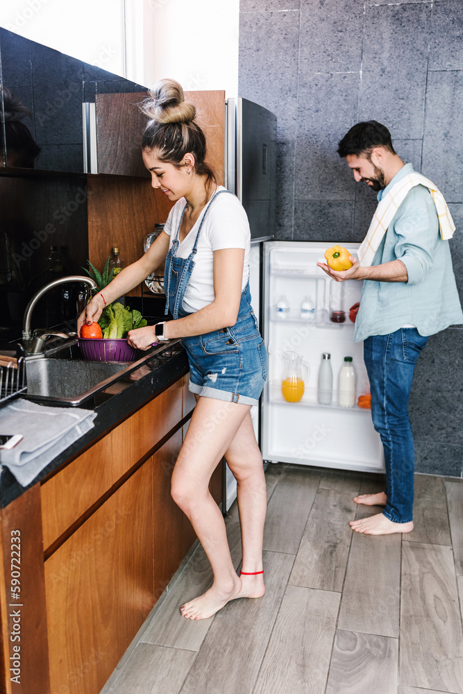 Obraz premium latin couple cooking together in the kitchen healthy food at home in Mexico, Hispanic people