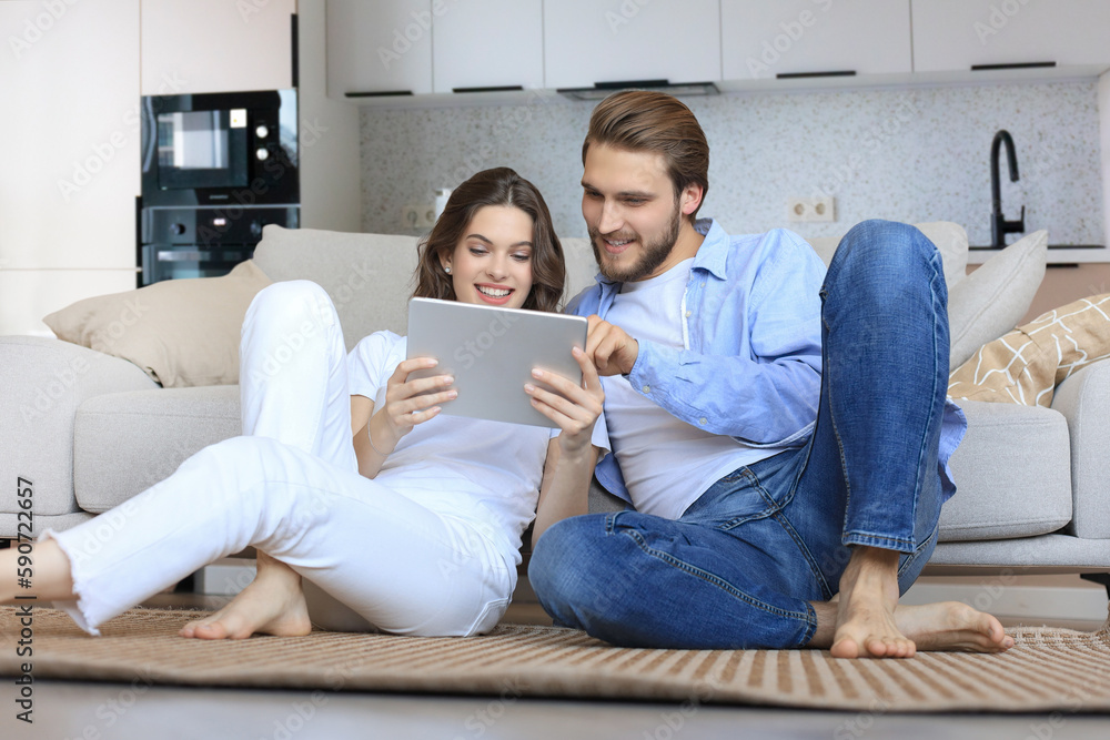 Happy couple sitting and planning new home decoration at home with a tablet, renovation and interior design for new house Happy couple sitting and planning new home decoration at home with a tablet, renovation and interior design for new house