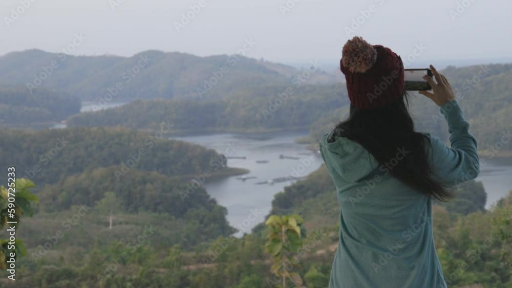 Rear view of attractive young Asian woman taking photo nature mountain landscape with mobile smart phone. Beautiful mountain landscape view. Rear view of attractive young Asian woman taking photo nature mountain landscape with mobile smart phone. Beautiful mountain landscape view.