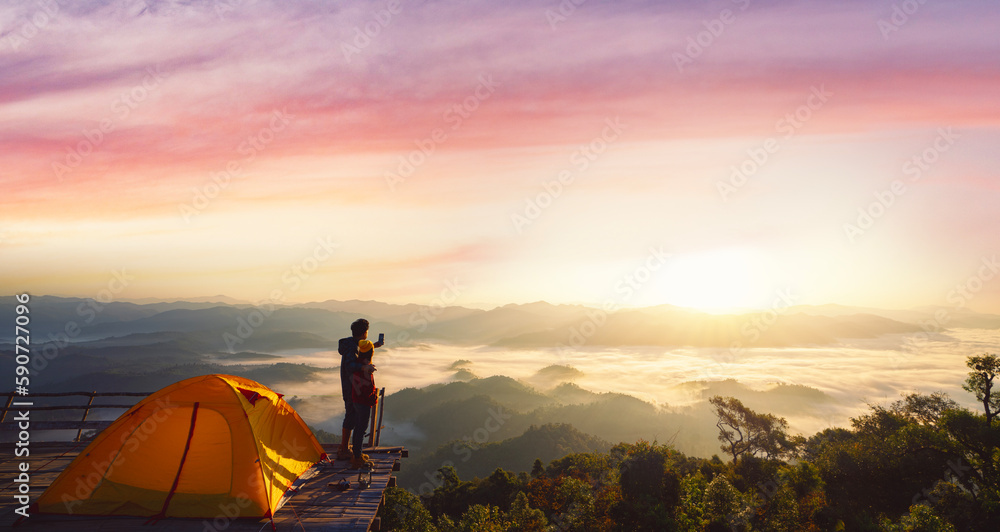 Asian couple enjoy in they tent at they camping point with morning sunrise view Asian couple enjoy in they tent at they camping point with morning sunrise view