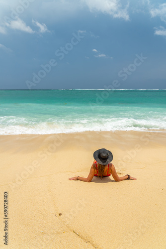 Woman with reb swimsuit and black hat at the beach in Bali indonesia