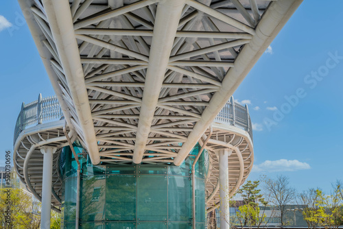 Underside of pedestrian walkway across street connected to glass building.