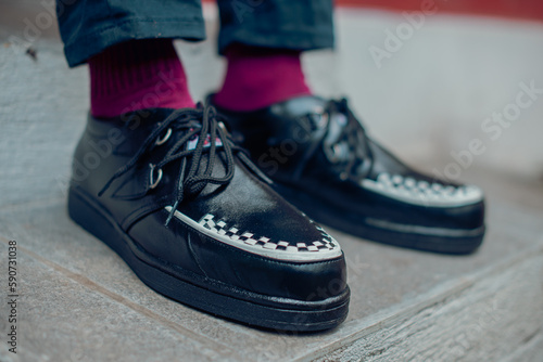 Young man sitting and wearing black genuine leather creepers sneakers. These casual yet elegant shoes are handmade by an at-home shoemaker  perfect for hanging out on a sunny day