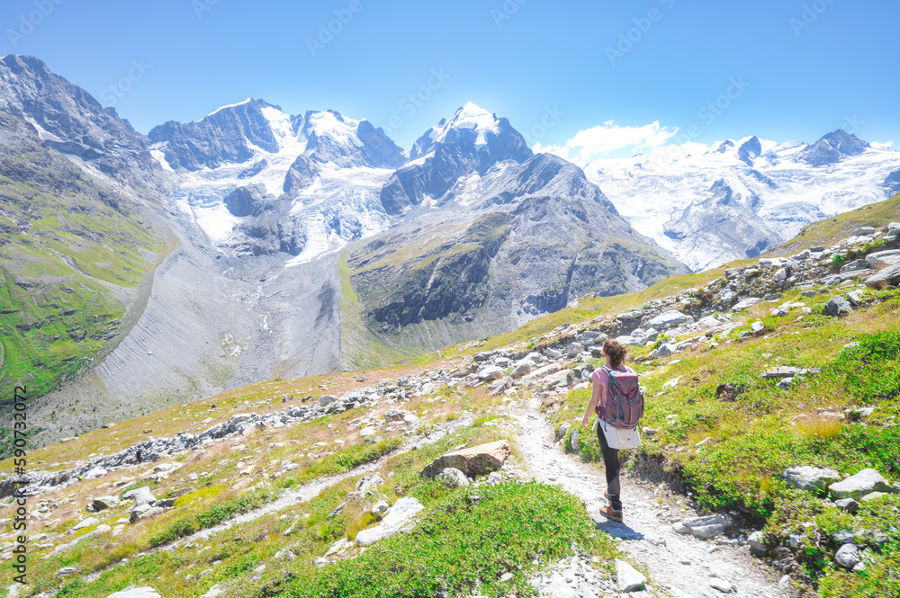A woman alone walks on high mountain trail