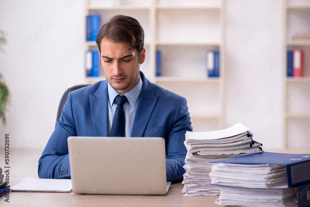 Young male employee and too much work in the office Young male employee and too much work in the office