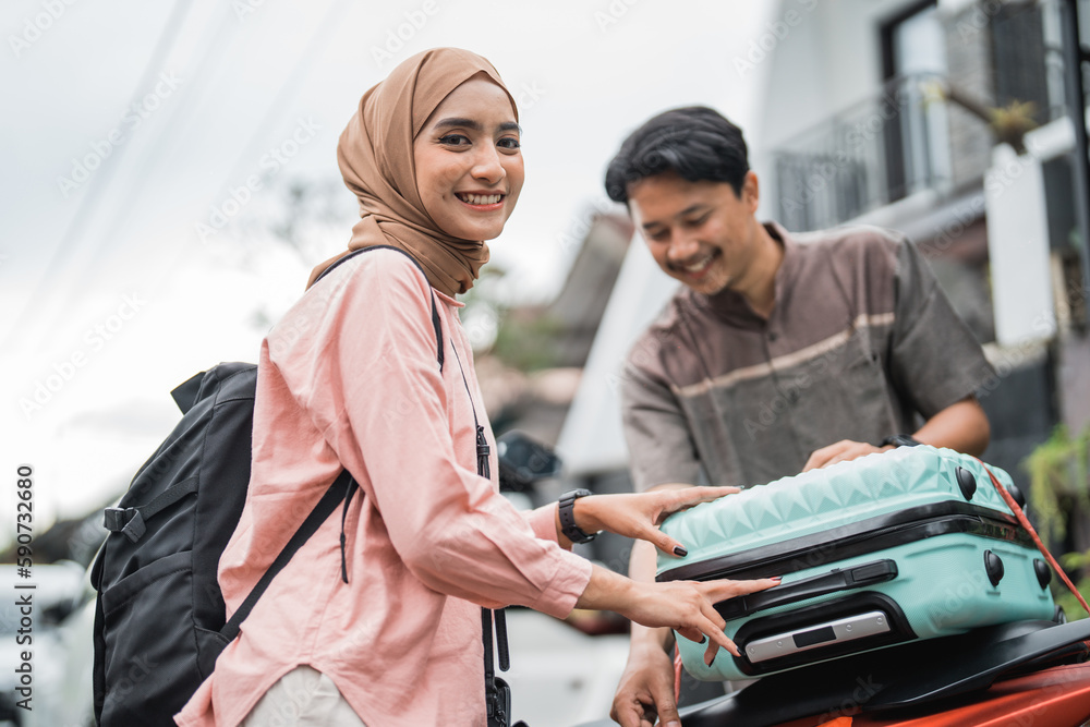 happy asian muslim couple pack his suitcase on motorbike travel during eid mubarak back to hometown