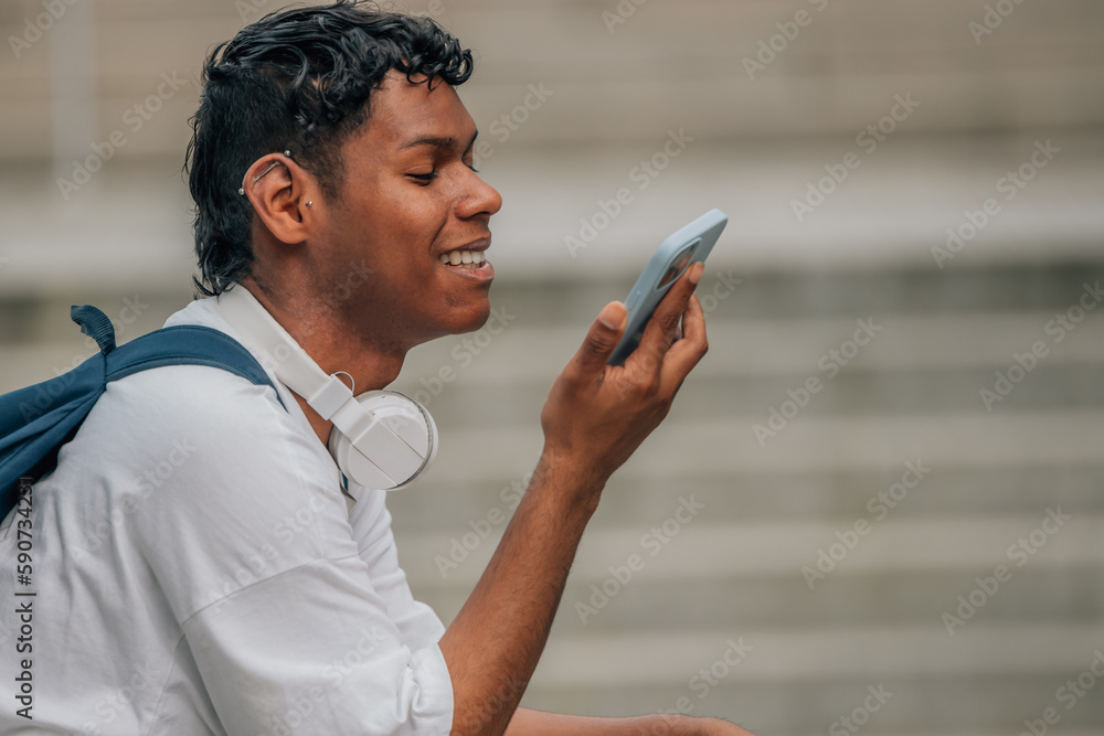 young latin man with mobile phone in the street talking or recording audio